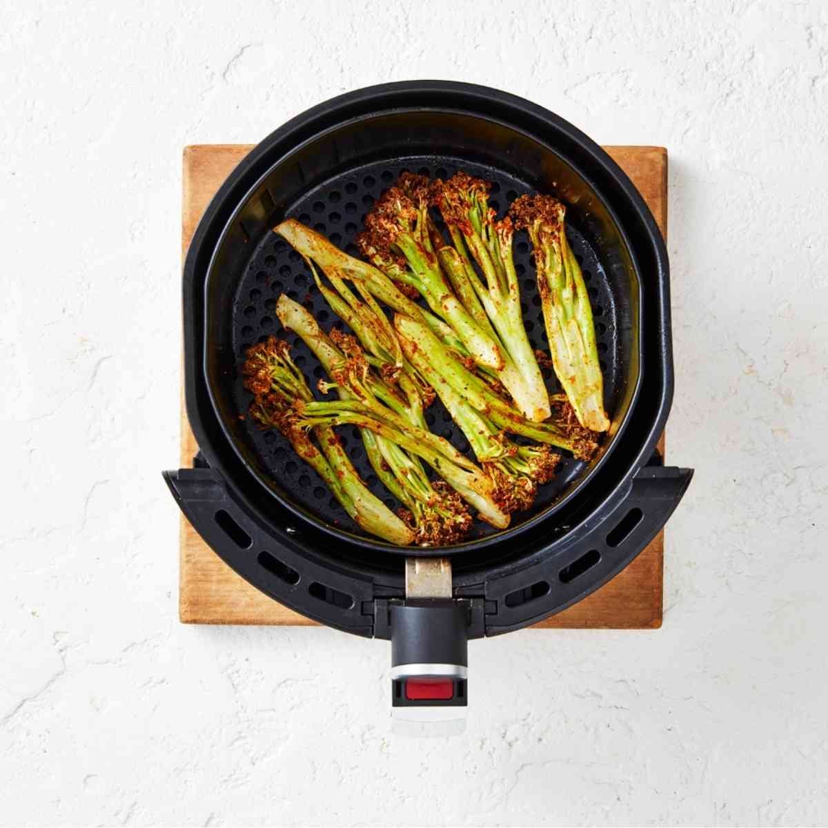 Cooked cauliblossom florets tossed in a mexican seasoning, placed in an air fryer.