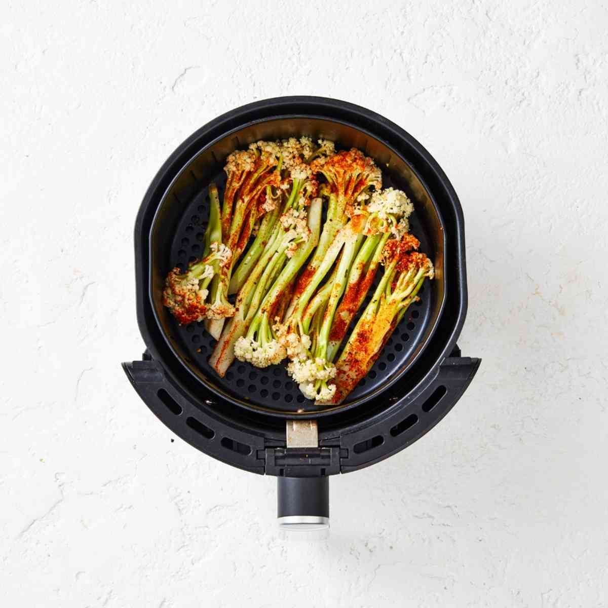 Cauliblossom florets tossed in a mexican seasoning, placed in an air fryer.