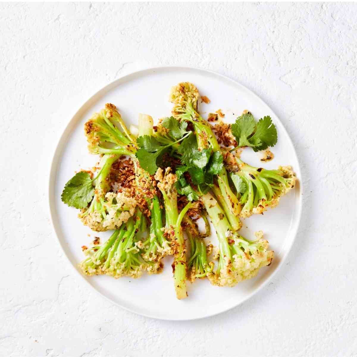 Stir fried cauliblossom florets with seasoning paste on a white plate. 